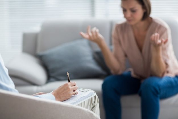 a woman sitting on a couch and writing on a clipboard